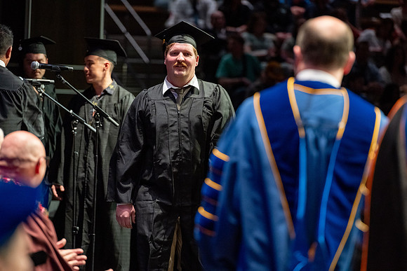 Graduates walk across the stage.