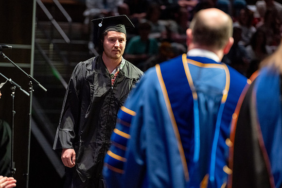 Graduates walk across the stage.
