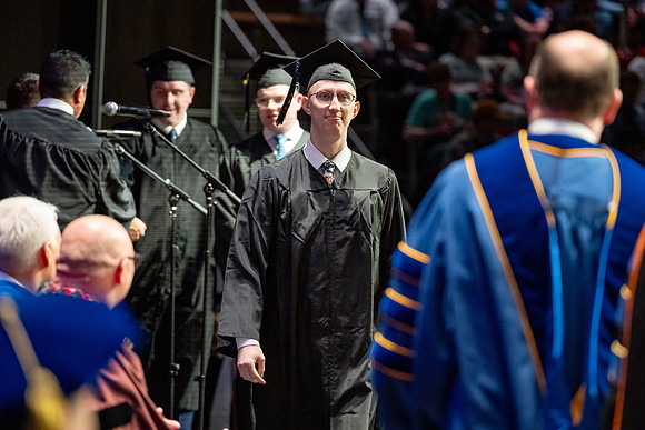 Graduates walk across the stage.