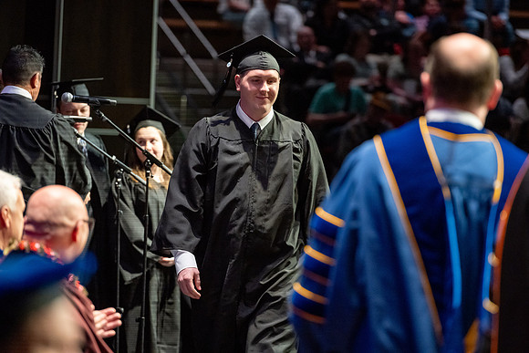 Graduates walk across the stage.