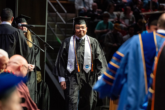 Graduates walk across the stage.