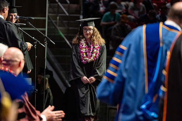 Graduates walk across the stage.