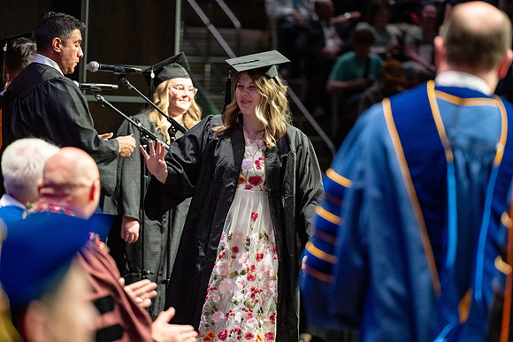 Graduates walk across the stage.