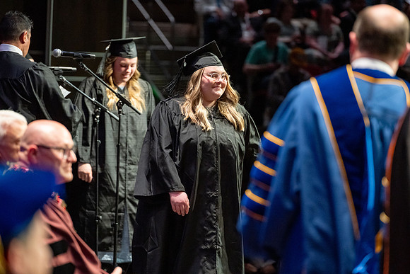 Graduates walk across the stage.