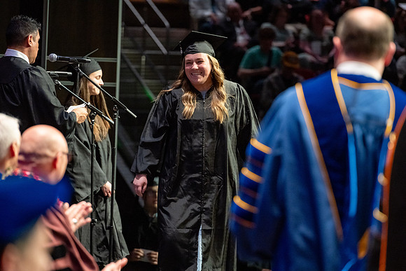 Graduates walk across the stage.