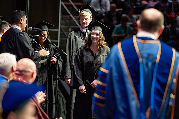 Graduates walk across the stage.