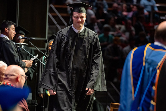 Graduates walk across the stage.