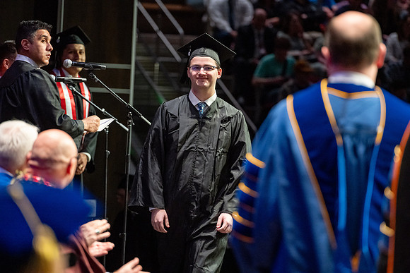 Graduates walk across the stage.