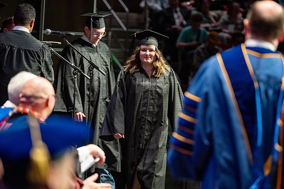 Graduates walk across the stage.