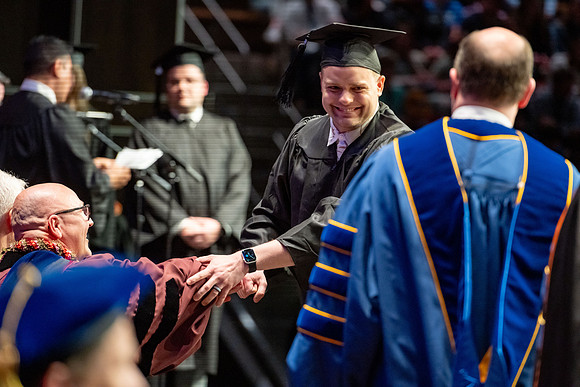 Graduates walk across the stage.