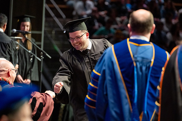 Graduates walk across the stage.