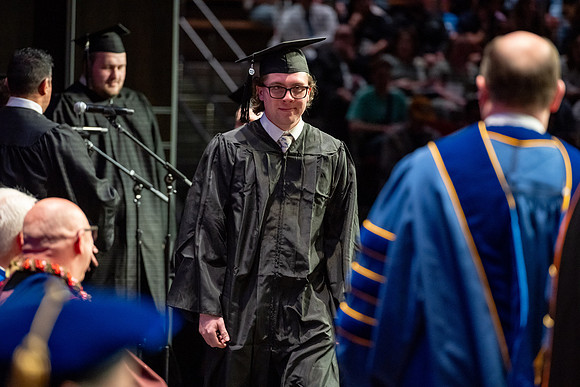 Graduates walk across the stage.