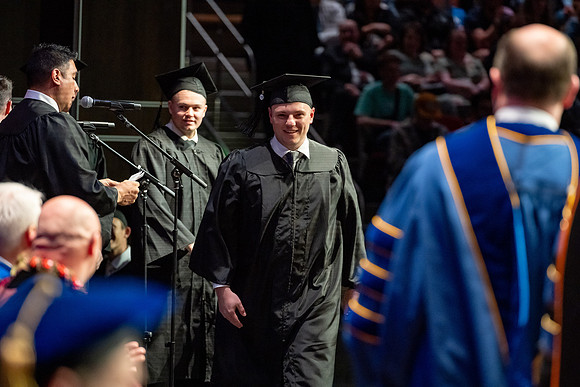 Graduates walk across the stage.