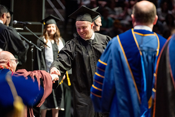 Graduates walk across the stage.