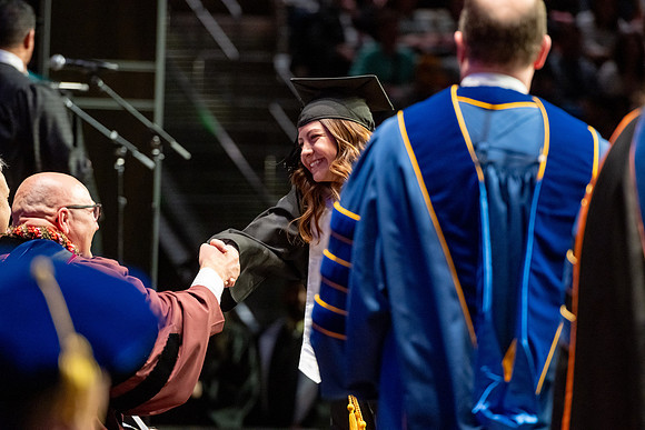 Graduates walk across the stage.