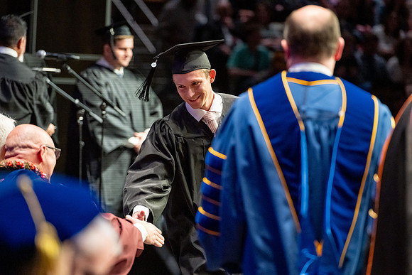 Graduates walk across the stage.