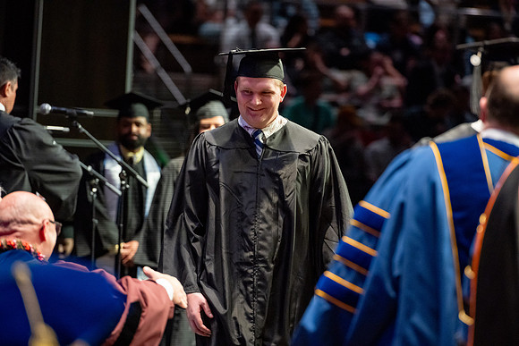 Graduates walk across the stage.