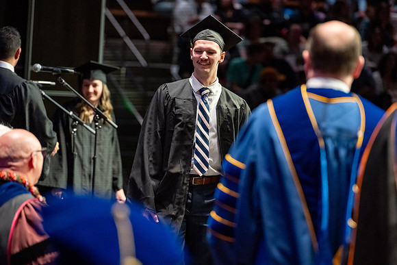 Graduates walk across the stage.