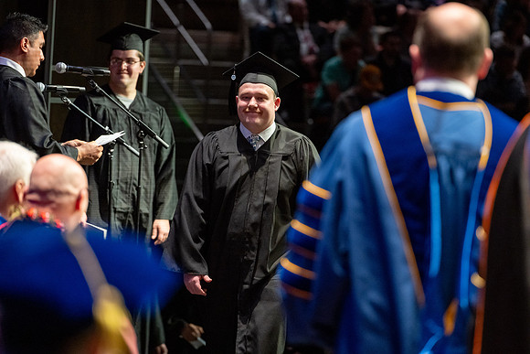 Graduates walk across the stage.