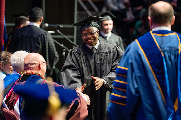 Graduates walk across the stage.