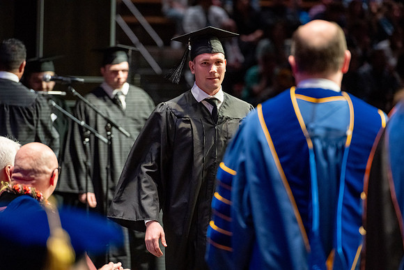Graduates walk across the stage.