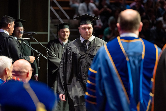 Graduates walk across the stage.