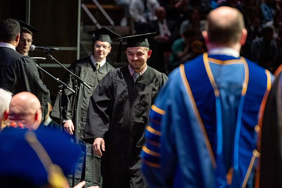Graduates walk across the stage.