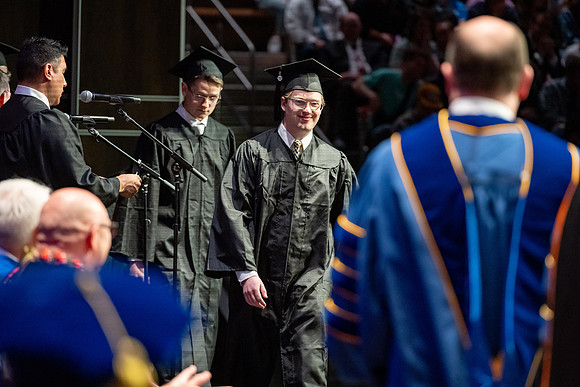Graduates walk across the stage.