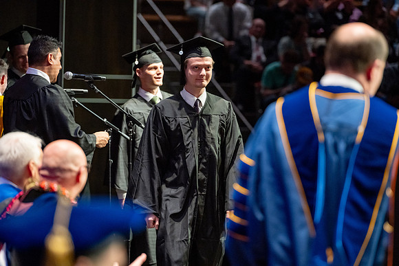 Graduates walk across the stage.
