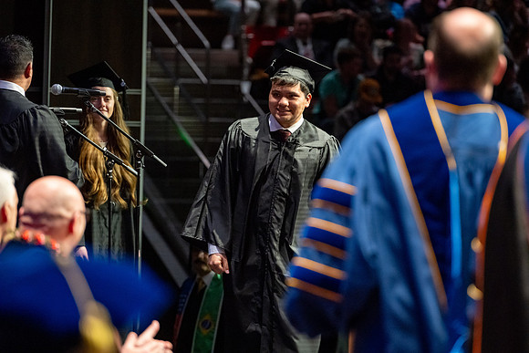 Graduates walk across the stage.