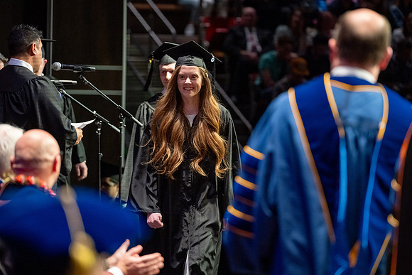 Graduates walk across the stage.