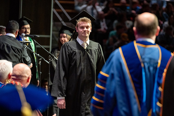 Graduates walk across the stage.