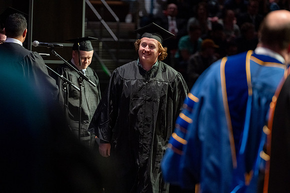Graduates walk across the stage.