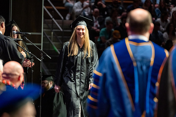 Graduates walk across the stage.