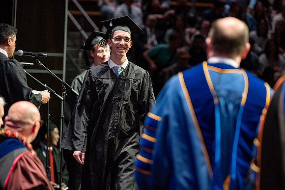 Graduates walk across the stage.