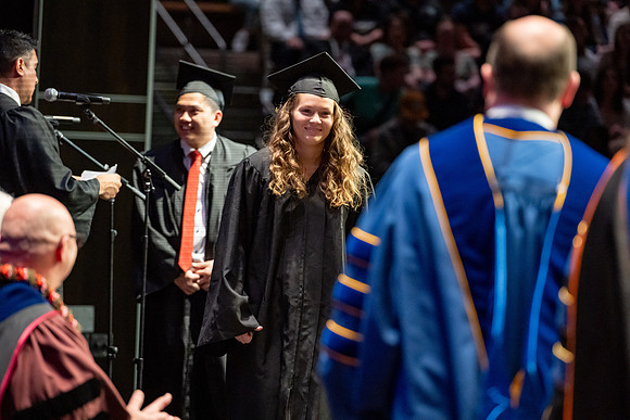 Graduates walk across the stage.
