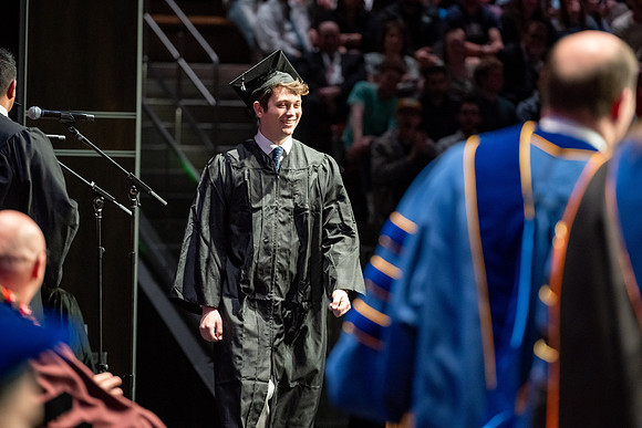 Graduates walk across the stage.