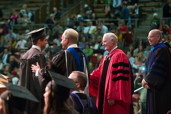 Elder W. Craig Zwick and President Kim B. Clark award diploma covers to graduates in the College of Business and Communication.