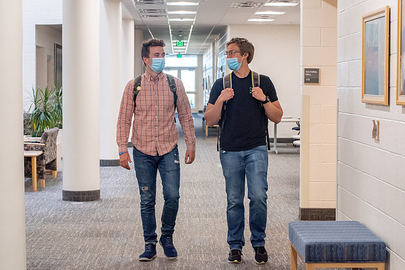 Examples of students staying safe and healthy during the COVID-19 pandemic by social distancing, following pathway arrows, and wearing face masks.