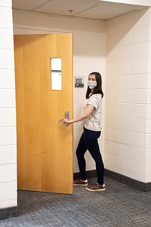 Examples of students staying safe and healthy during the COVID-19 pandemic by social distancing, following pathway arrows, and wearing face masks.