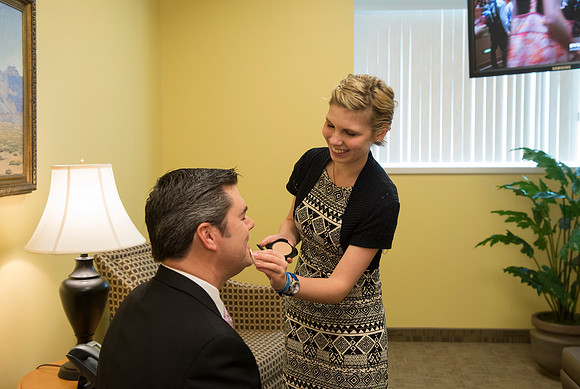 Behind the scenes of devotional, the speaker, Drew Eader, gets a little powder to reduce the shine from the bright lights.