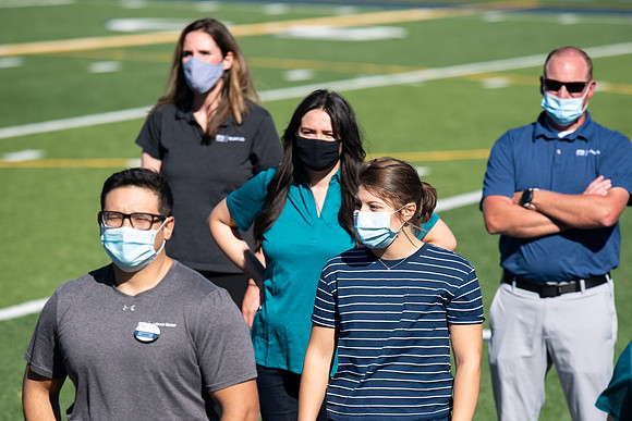 Examples of students staying safe and healthy during the COVID-19 pandemic by social distancing, following pathway arrows, and wearing face masks.