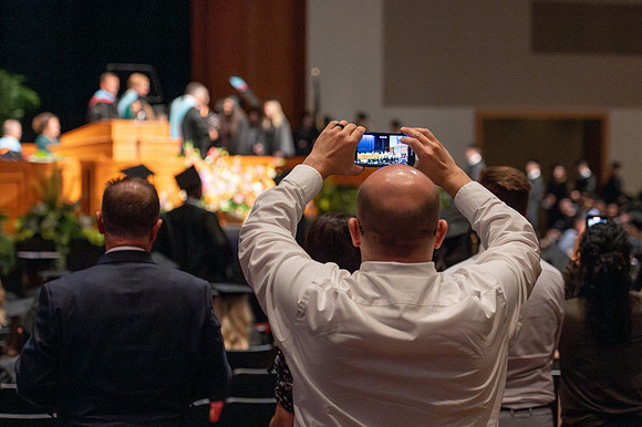 Brother Timothy Rarick laughs with graduates during convocation for the College of Education & Human Development