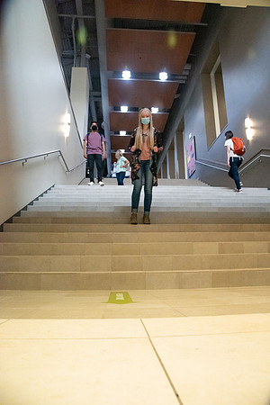 Examples of students staying safe and healthy during the COVID-19 pandemic by social distancing, following pathway arrows, and wearing face masks.