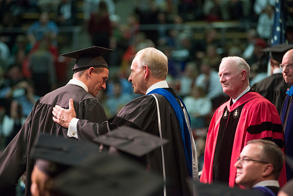 Elder W. Craig Zwick and President Kim B. Clark award diploma covers to graduates in the College of Business and Communication.