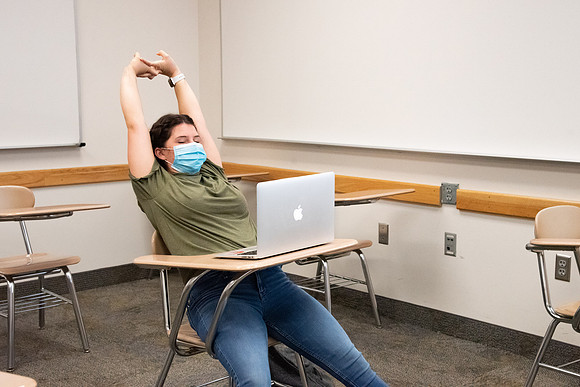 Examples of students staying safe and healthy during the COVID-19 pandemic by social distancing, following pathway arrows, and wearing face masks.