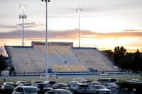 The stadium during sunset with people going up and down the bleacher stairs