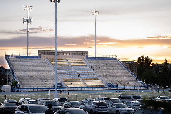 The stadium during sunset with people going up and down the bleacher stairs