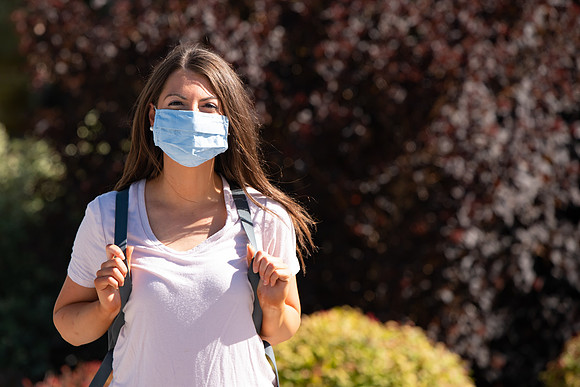 Examples of students staying safe and healthy during the COVID-19 pandemic by social distancing, following pathway arrows, and wearing face masks.