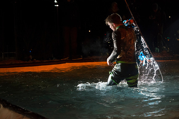 Students make a run down a snowy slope and across a pond of water in the annual event of Pond Skimming.